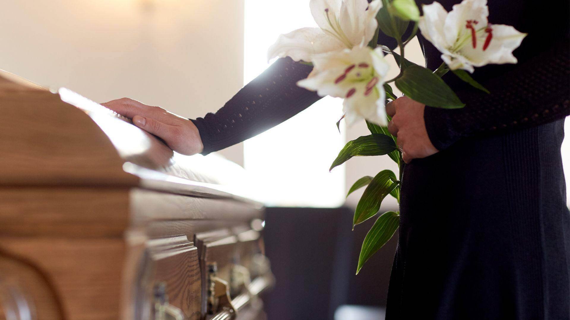 person-mourning-touching-a-casket-with-flowers-in-alexander-city